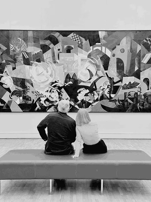 un uomo e una donna seduti a guardare un'opera d'arte appesa al muro. l'imagine rappresenta. far i tipi di amore, quello dell'amicizia